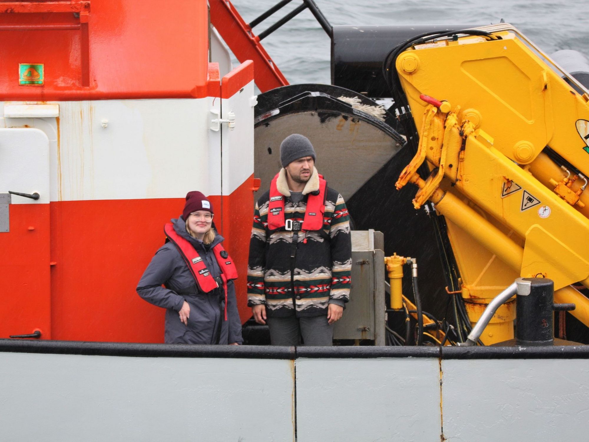 Schiffswechsel bei Seegang – zwei Personen schauen vom Lotsenboot zum Schiff.