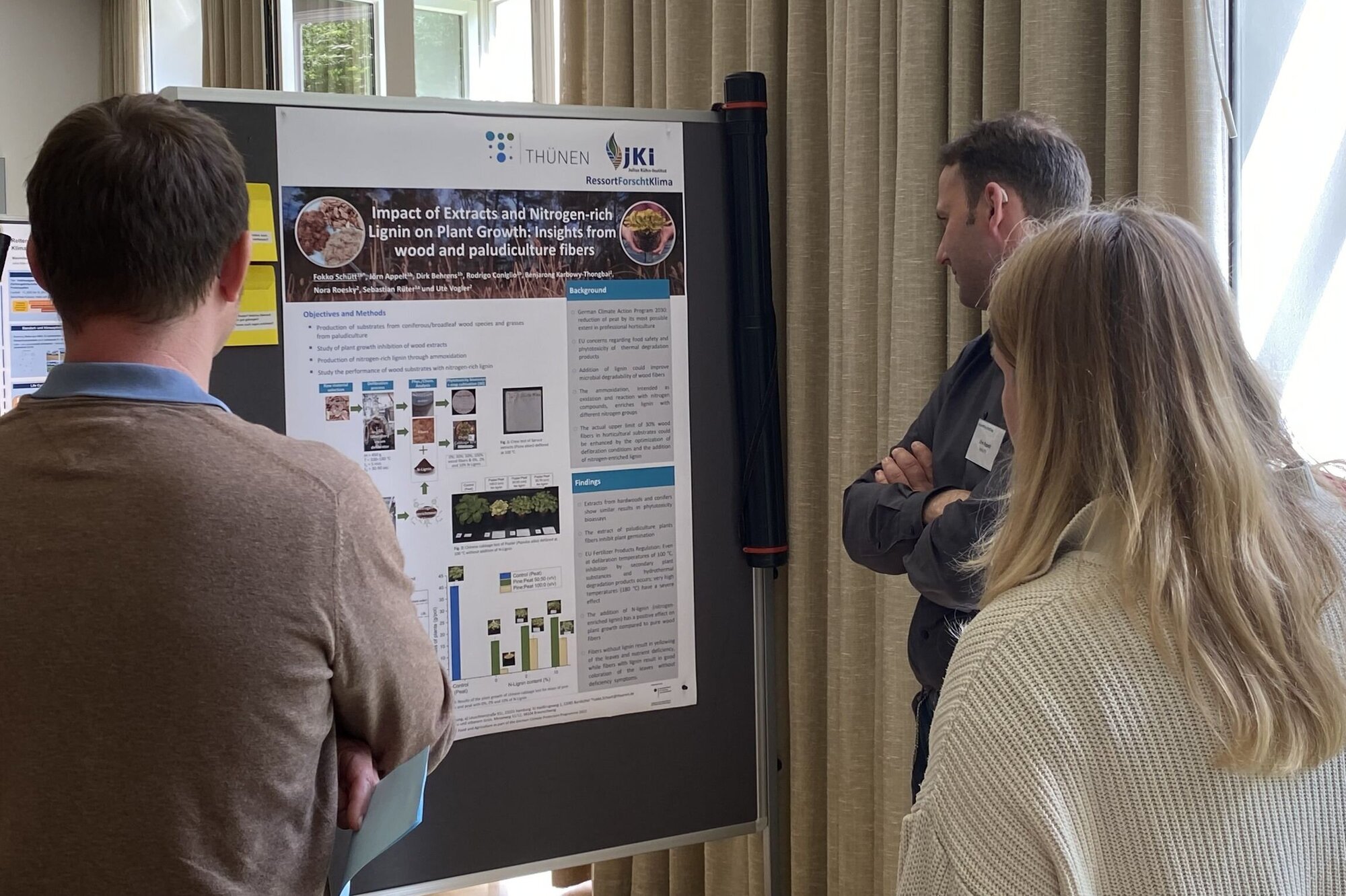 Drei Personen vor Poster