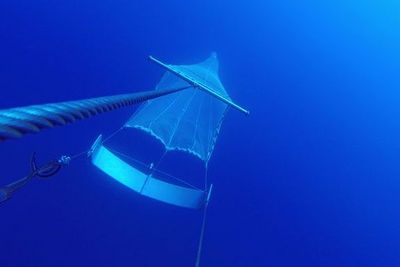An einer Trosse gezogenes Planktonnetz im tiefblauen Meer, unter Wasser.