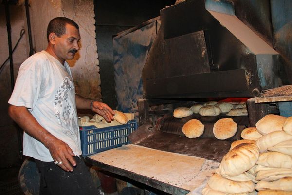 In Ägypten steht ein Bäcker vor seiner Backstraße, aus der frische Fladenbrote kommen.