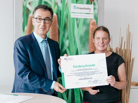 Bundeslandwirtschaftsminister Cem Özdemir und Dr. Bärbel Tiemeyer präsentieren die Förderurkunde für das Projekt