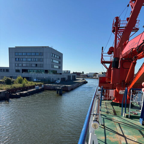 The ship's railing can be seen, with the Thünen Institute building in Bremerhaven in the background.