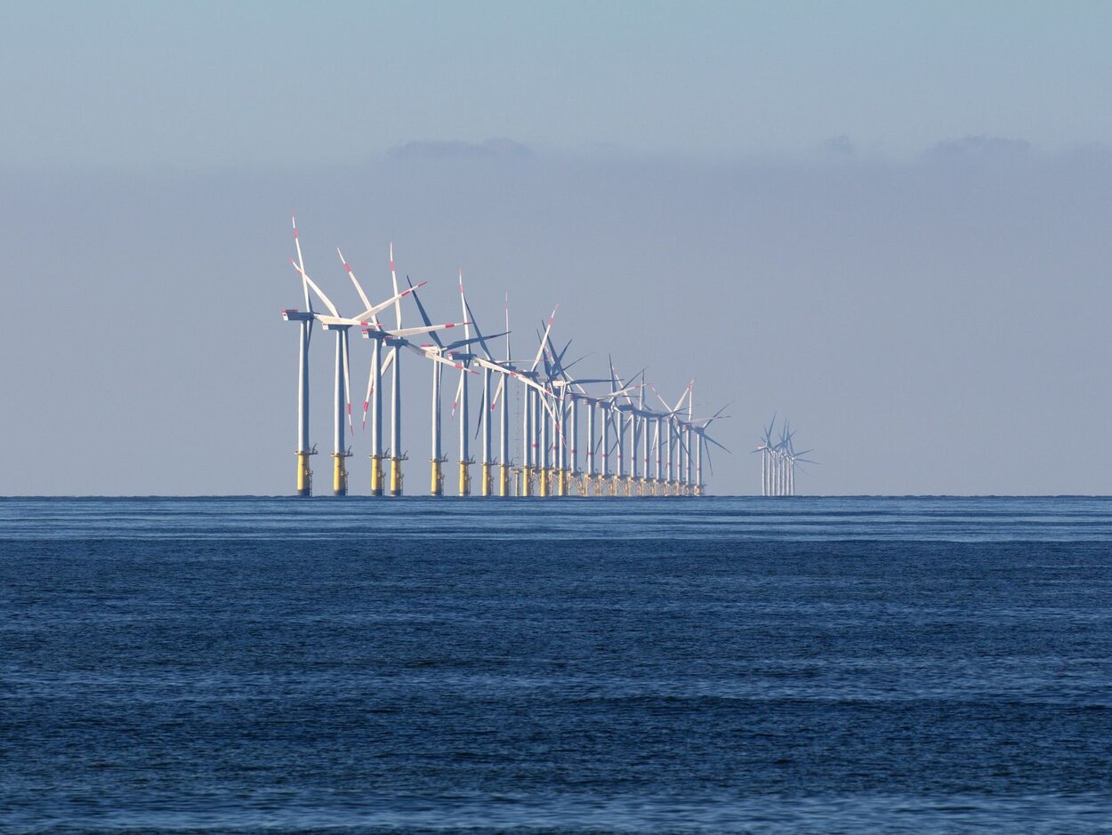 Mitten im Meer stehen einige Windräder.