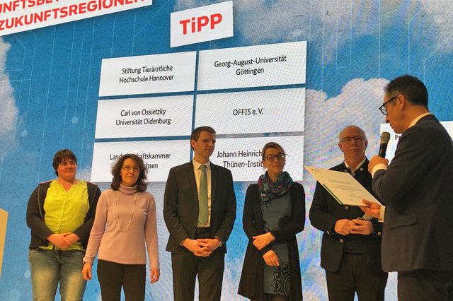 Auf der Bühne der BMEL-Halle überreicht Bundesminister Cem Özdemir den Förderbescheid für das Verbundprojekt TiPP.