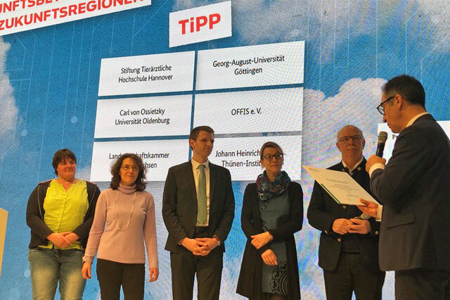 Auf der Bühne der BMEL-Halle überreicht Bundesminister Cem Özdemir den Förderbescheid für das Verbundprojekt TiPP.