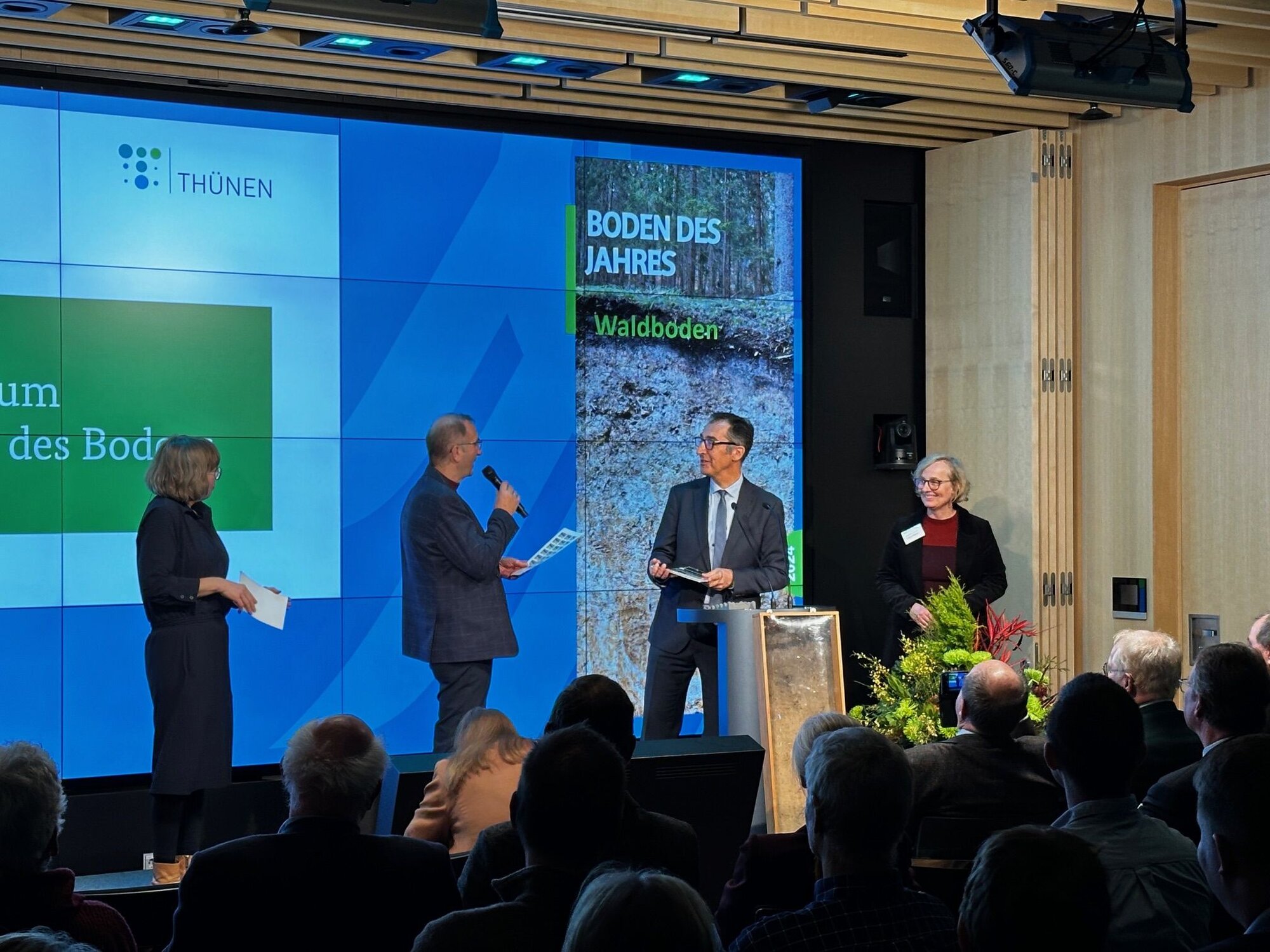 Hanna Gersmann (Moderation), Gerhard Milbert (Konsortium Boden des Jahres), Cem Özdemir (Bundesminister) und Nicole Wellbrock (Thünen-Institut) bei der Festveranstaltung zum Boden des Jahres 2024. 