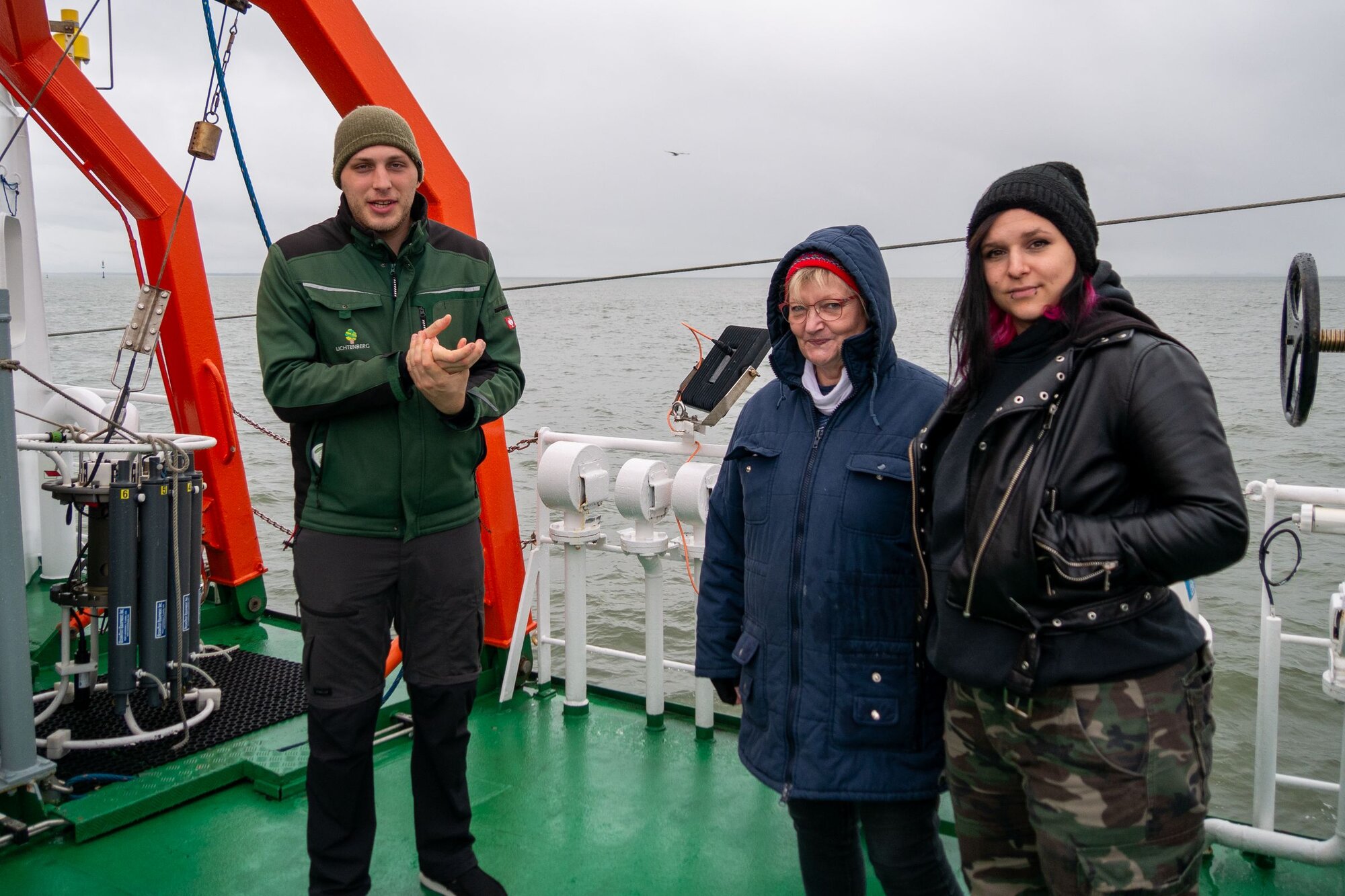 Eine Sicherheitsübung pro Reise ist Pflicht, dann heißt es alle zum Sammelpunkt mit Jacke, festem Schuhwerk und Mütze. Drei Mitfahrer stehen an Deck.