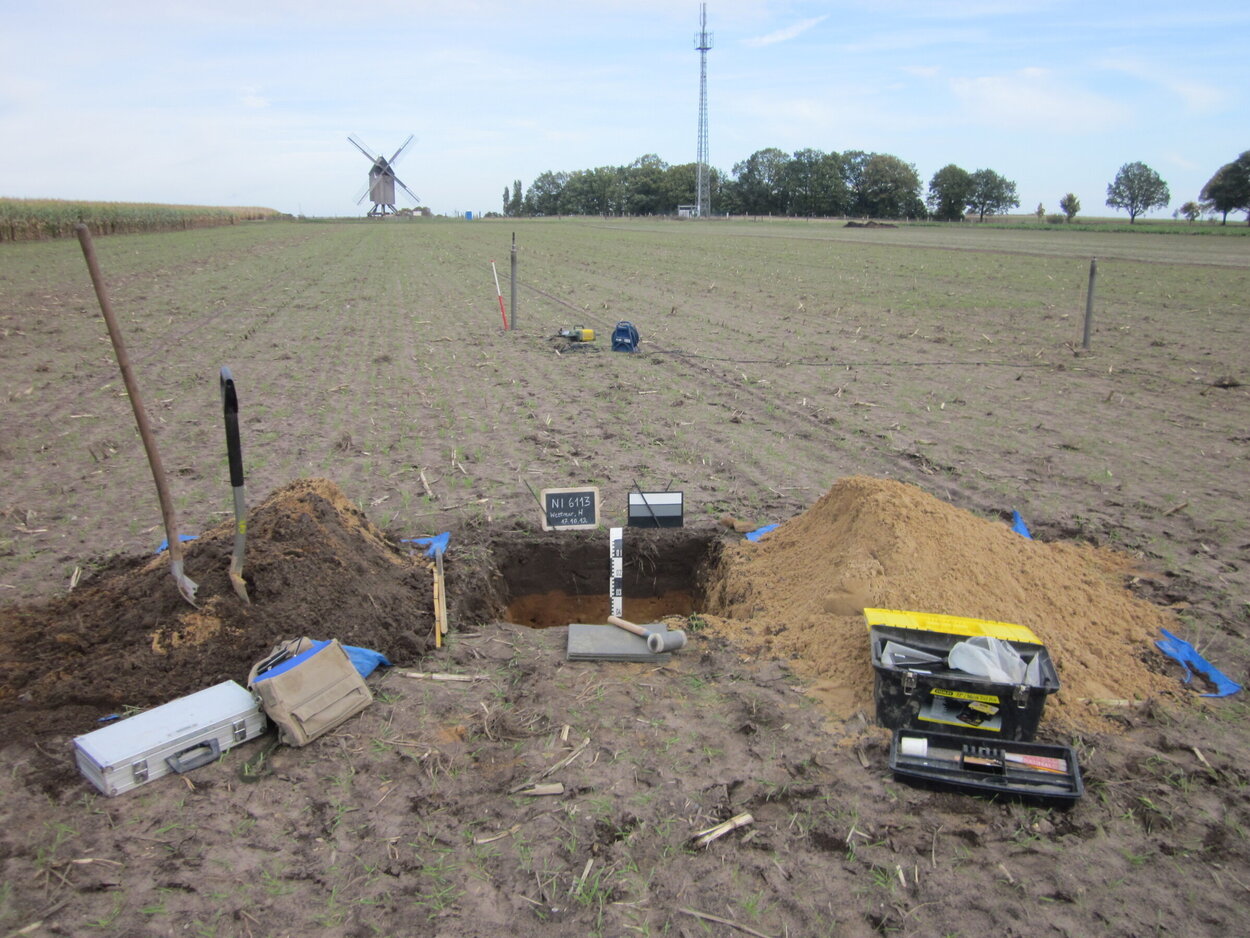 Ein Grube in einem Feld mit Werkzeug darum herum.