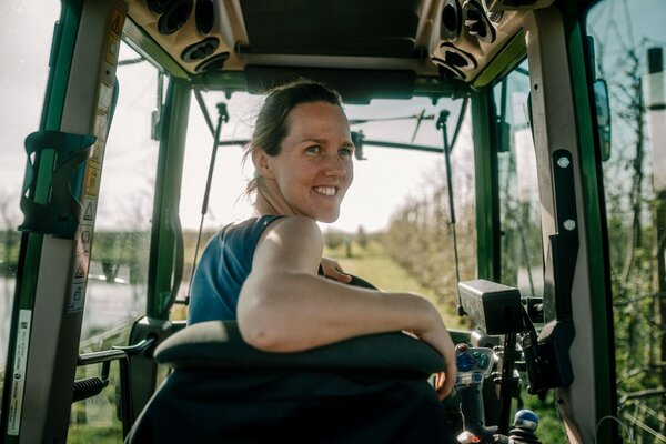 Eine Frau sitzt auf dem Fahrersitz eines Teckers und schaut nach hinten aus dem Fenster.