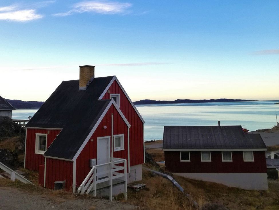 Eine Gruppe kleiner Holzhäuser am Wasser auf Grönland.