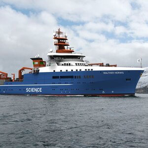 Ein in blau, weiß und orange gestrichenes Schiff auf dem Meer.