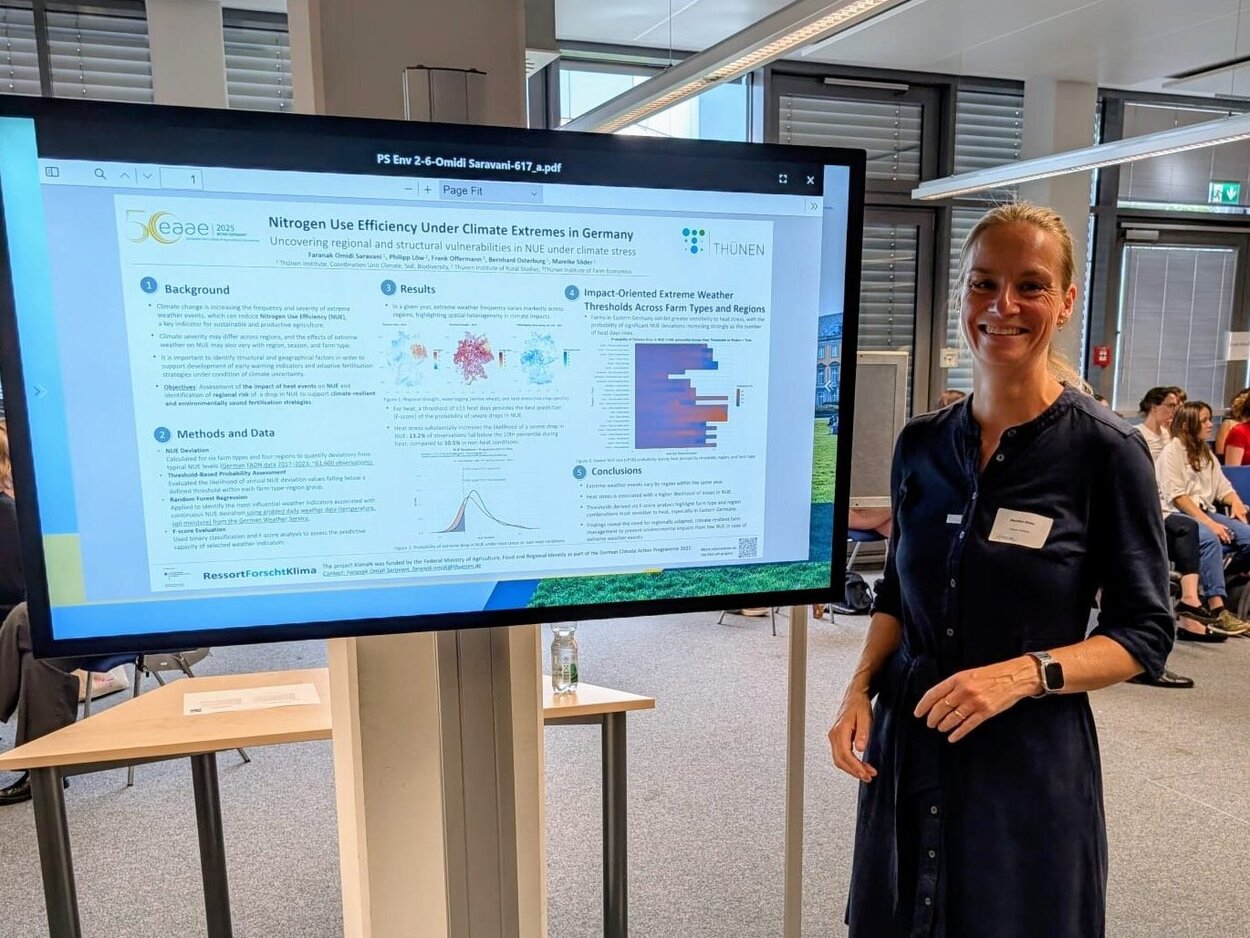 Eine Person steht vor einem großen Monitor auf dem ein Poster präsentiert wird.