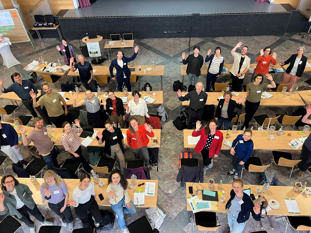 Teilnehmer*innen des Vernetzungstreffens winken in die Kamera