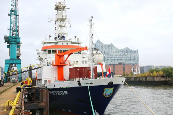 Das Forschungsschiff Meteor liegt an der Pier in Hamburg. Im Hintergrund die Elbphilarmonie.