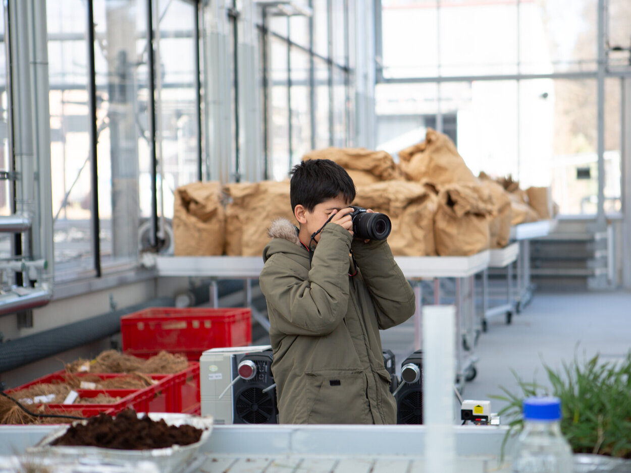 Ein Kind macht ein Foto mit einer professionellen Kamera.