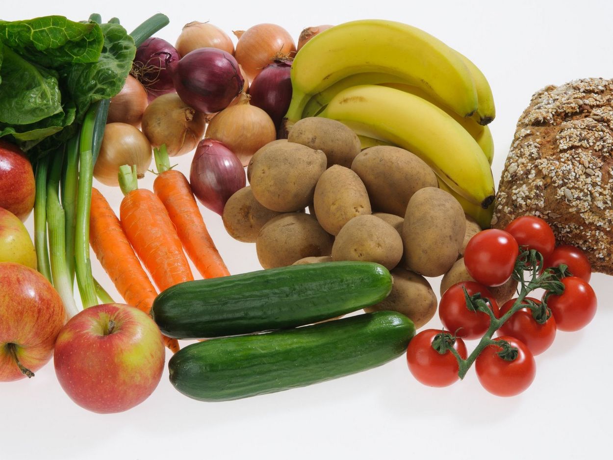 Das Foto zeigt verschiedene Obst- und Gemüsearten und Vollkornbrot als Komponenten einer pflanzenbasierten Ernährung.