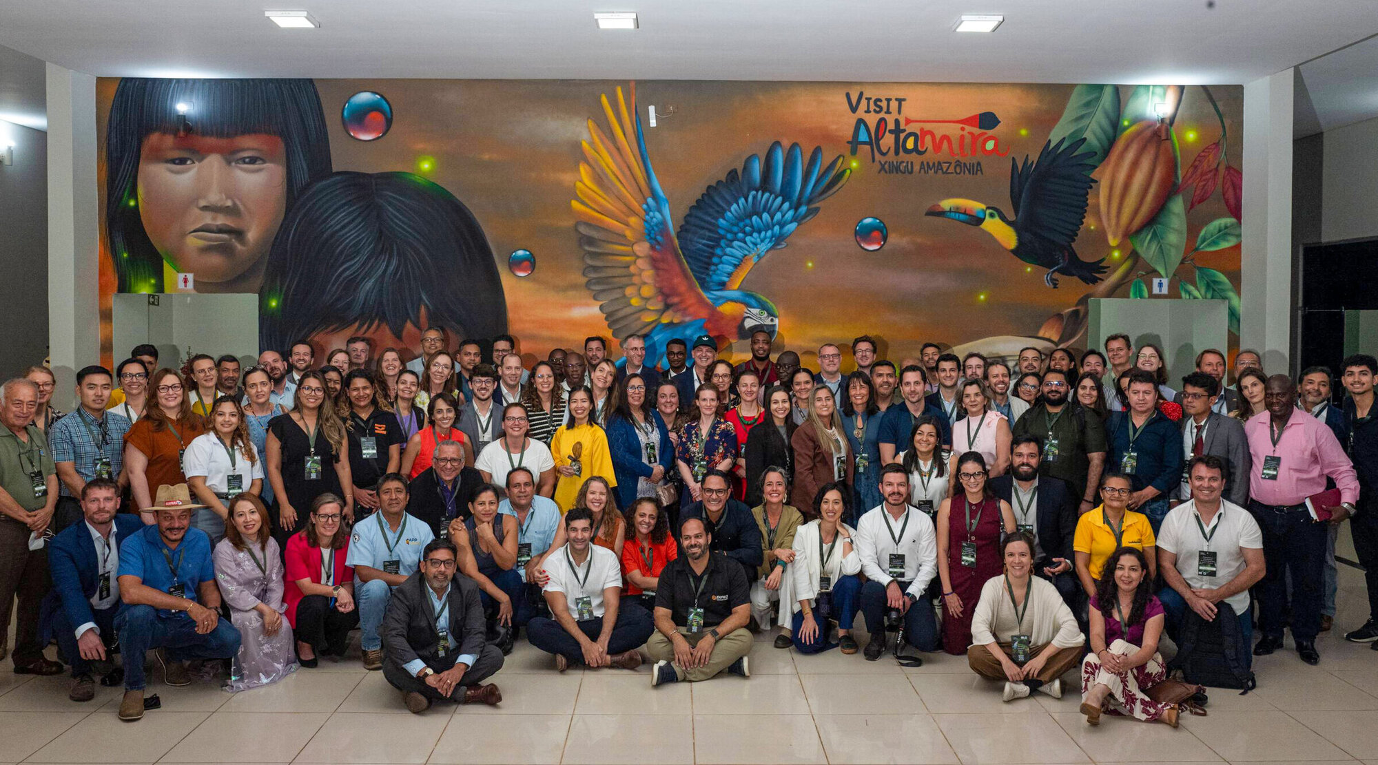 Eine große Gruppe Menschen vor einem bunten Wandbild.