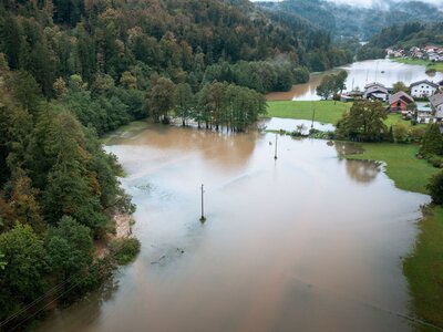Luftaufnahme einer Überschwemmung Ein Feld, ein Wald und ein Dorf stehen teilweise unter Wasser