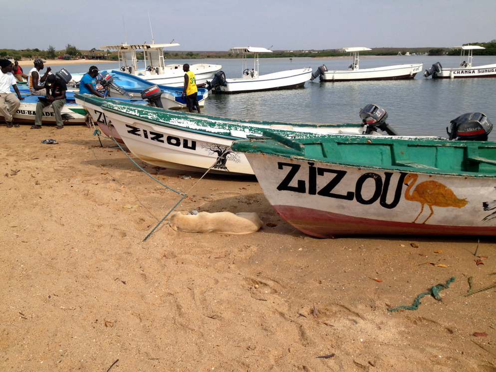 Kleine Fischerboote mit Fischern auf einem Strand in Westafrika.