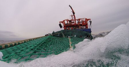 Blick über das Netz im Wasser auf das Fischereiforschungsschiff Solea
