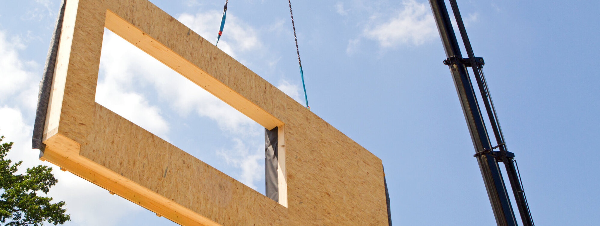 Ein Teil des Hauses wird gerade vom Kran in die Höhe gezogen.