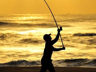 Ein Angler abends am Strand im Gegenlicht