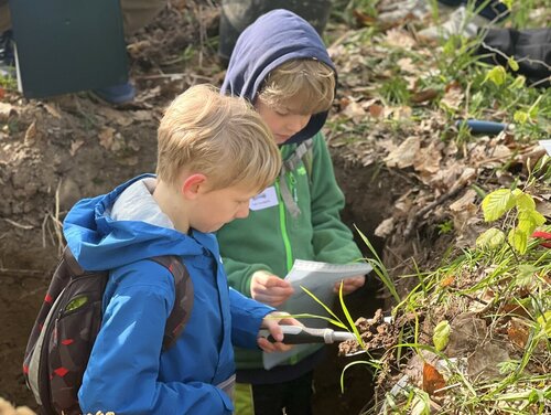 Zwei Kinder stehen in einer Bodengrube.