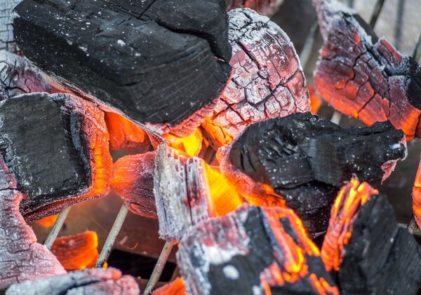 Das Bild zeigt glühende Holzbriketts in einer Grillschale.