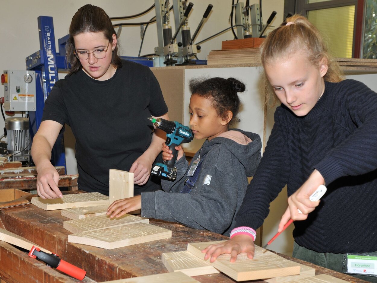 Zukunftstag 2024 Drei Personen führen Holzarbeiten aus