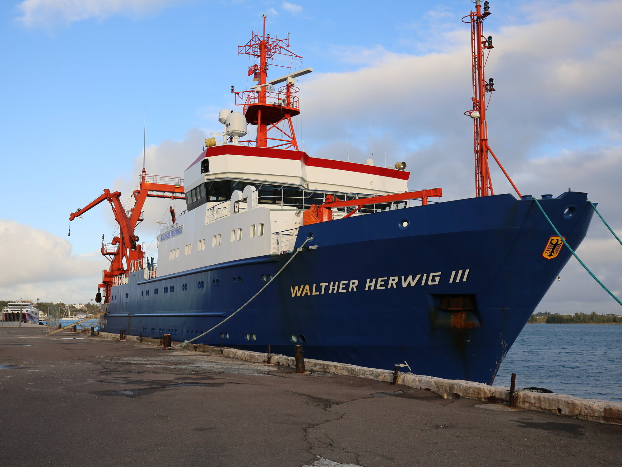 Das Forschungsschiff Walther Herwig III liegt in einem Hafen, der Himmel ist blau mit ein paar Wolken.