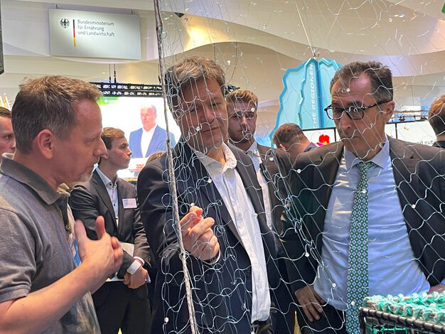 Die Minister Robert Habeck und Cem Özdemir lassen sich am Stand des Thünen-Instituts von einem Mitarbeiter die Arbeitsweise des Perlennetzes erläutern.