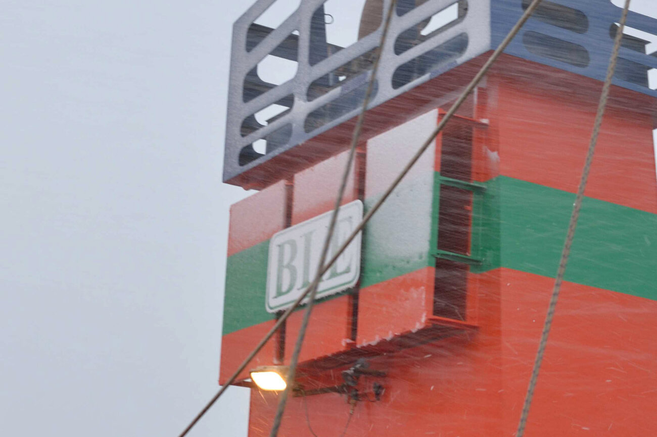 Schneefall im Vordergrund, der Schiffsschornstein im Hintergrund.