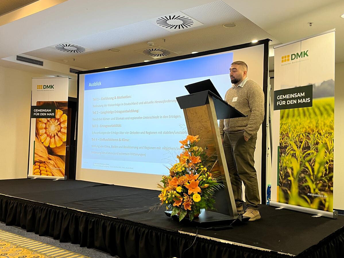 Auf dem Maiskomitee ist Masud Heydarli auf einem Rednerpult zu sehen.