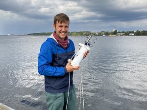 A person is standing by the sea with a cylindrical white device.