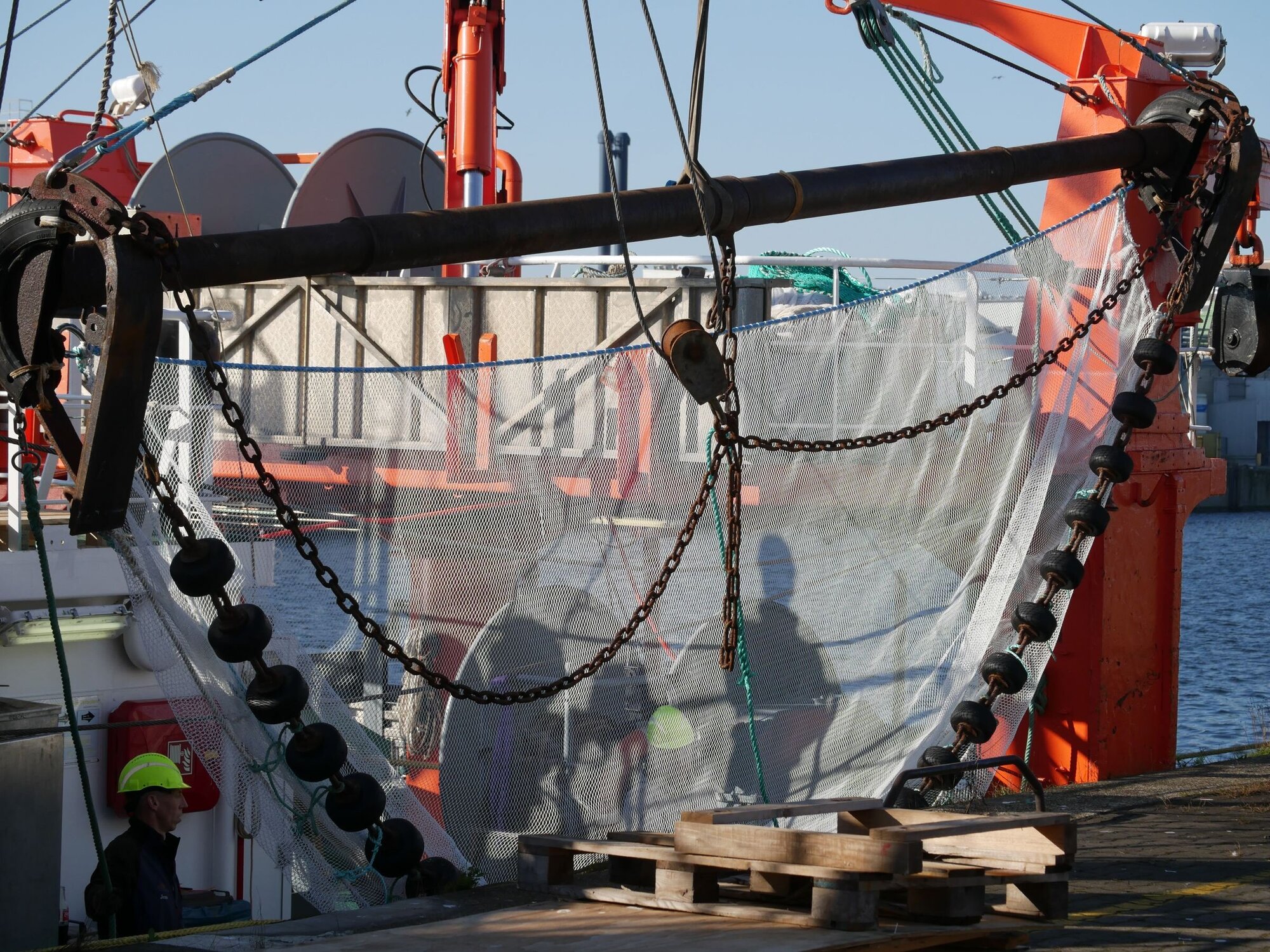 Die Baumkurre auf der Backbordseite. Blick auf die Baumkurre, ein Metallrohr mit Kufen hält das Netz mit einem Rollen für den Boden auf.
