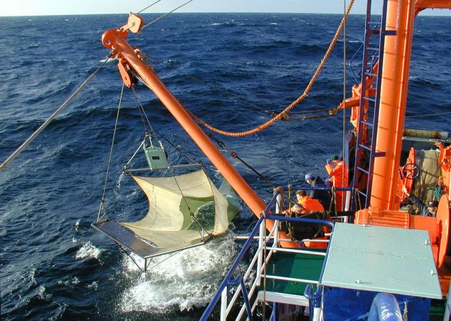 Ein Planktonnetz hängt neben im Schiff im Wasser
