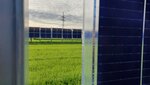 Blick zwischen zwei Agri-PV anlagen auf ein Feld auf dem auch Agri-PV Elemente stehen.