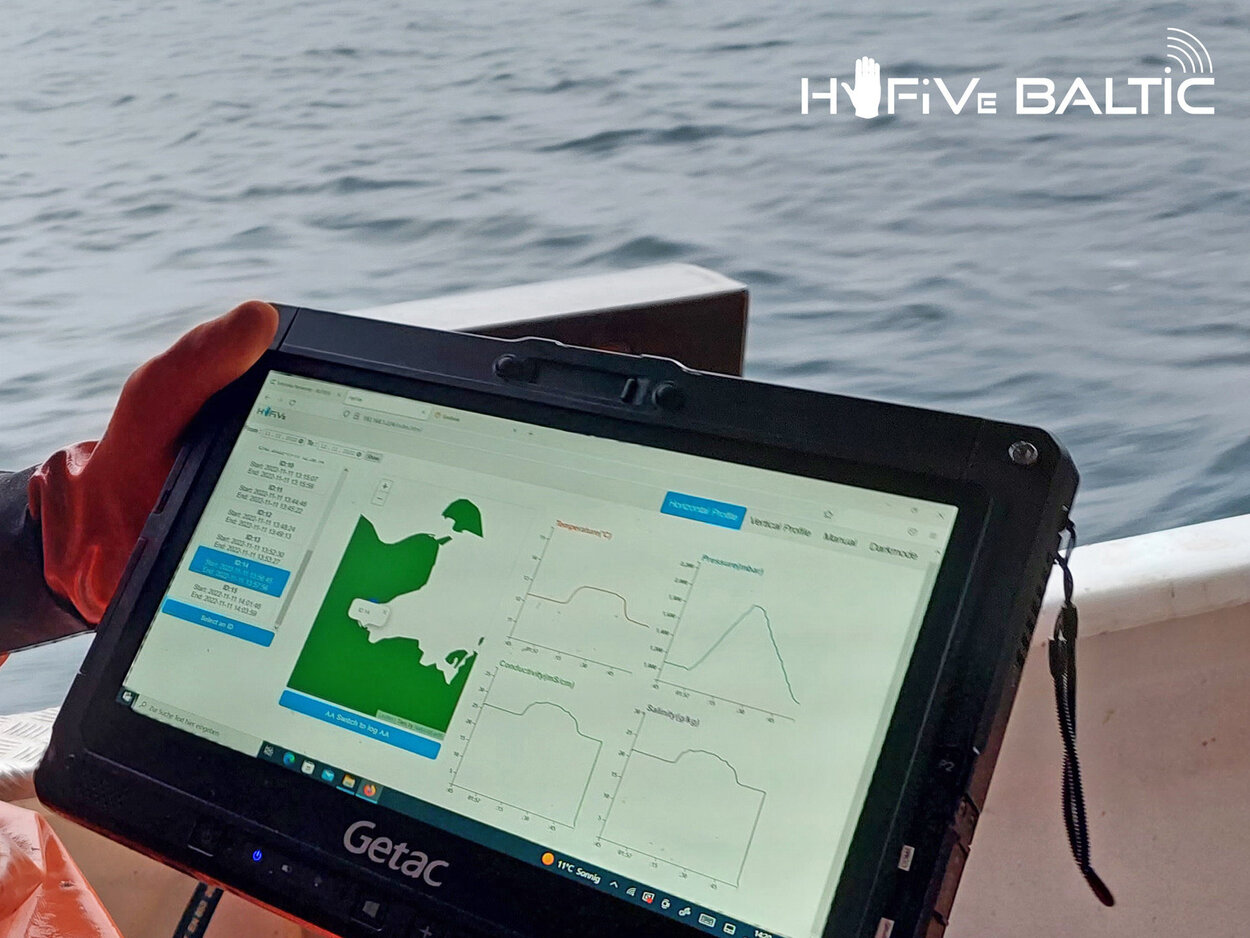 A fisherman on a small cutter holds a monitor with measurement data in his hand.