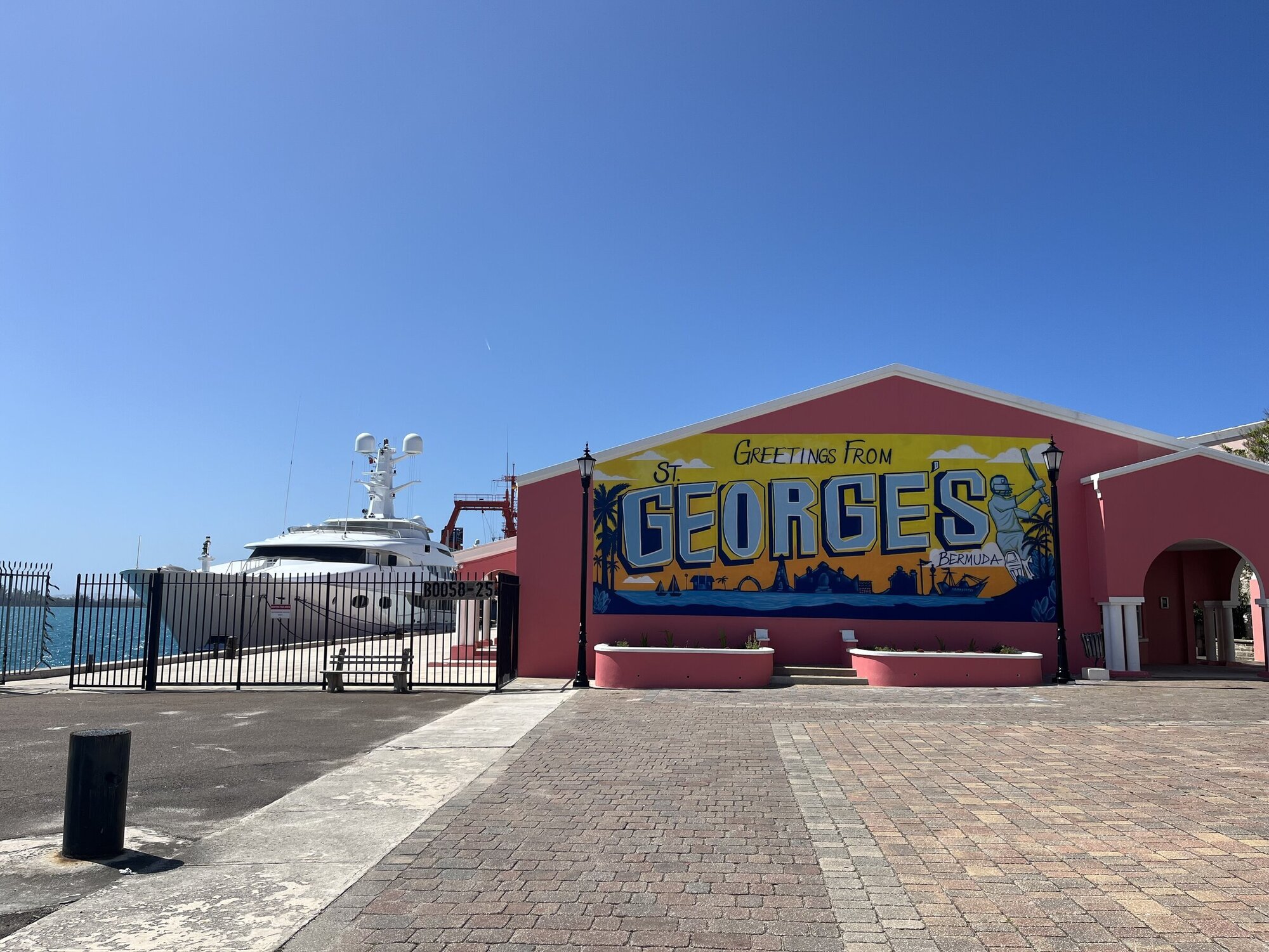 Eine Hütte mit Werbung für St. George auf den Bermudas ein weißes Schiff liegt auf der linken Seite daneben.