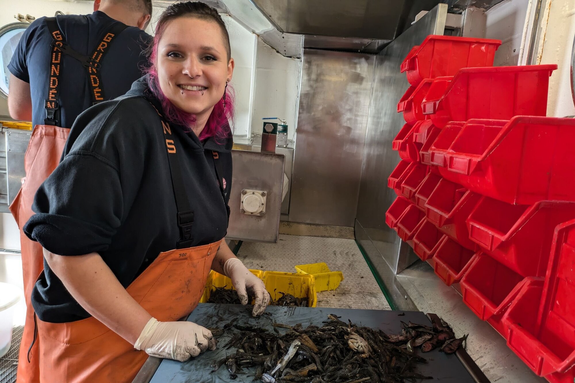 Unsere Fahrtleiterin Annie bei der Krabbenfeinsortierung. Eine Frau steht vor einem blauen Brett mit dem Krabbenfang.