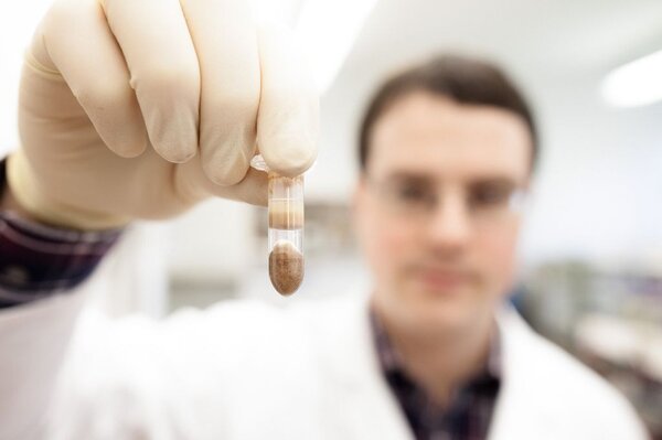 Ein Mitarbeiter hält das Glas mit der zerkleinerten Zellstruktur nach vorn.