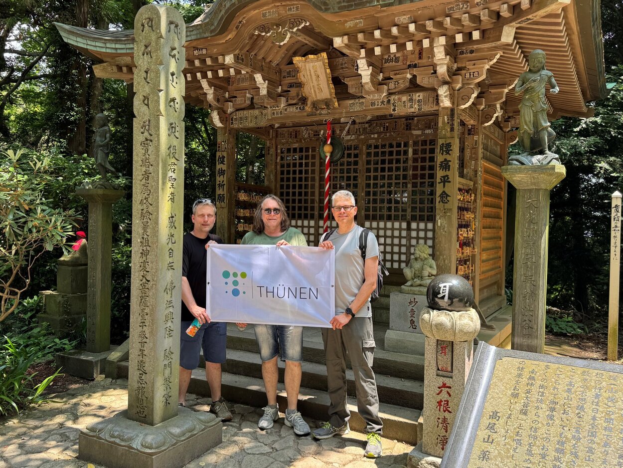 Drei Wissenschaftler vom Thünen Institut in Japan halten eine Fahne mit dem Thünen Schriftzug.