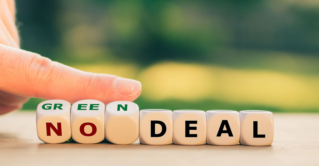 A hand changes a row of dice with letters on them. It now shows “green deal” instead of “no deal”. 