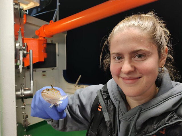 Die Biologie-Studentin Laura Thiel hält an Bord der Solea einen Fisch in der Hand.