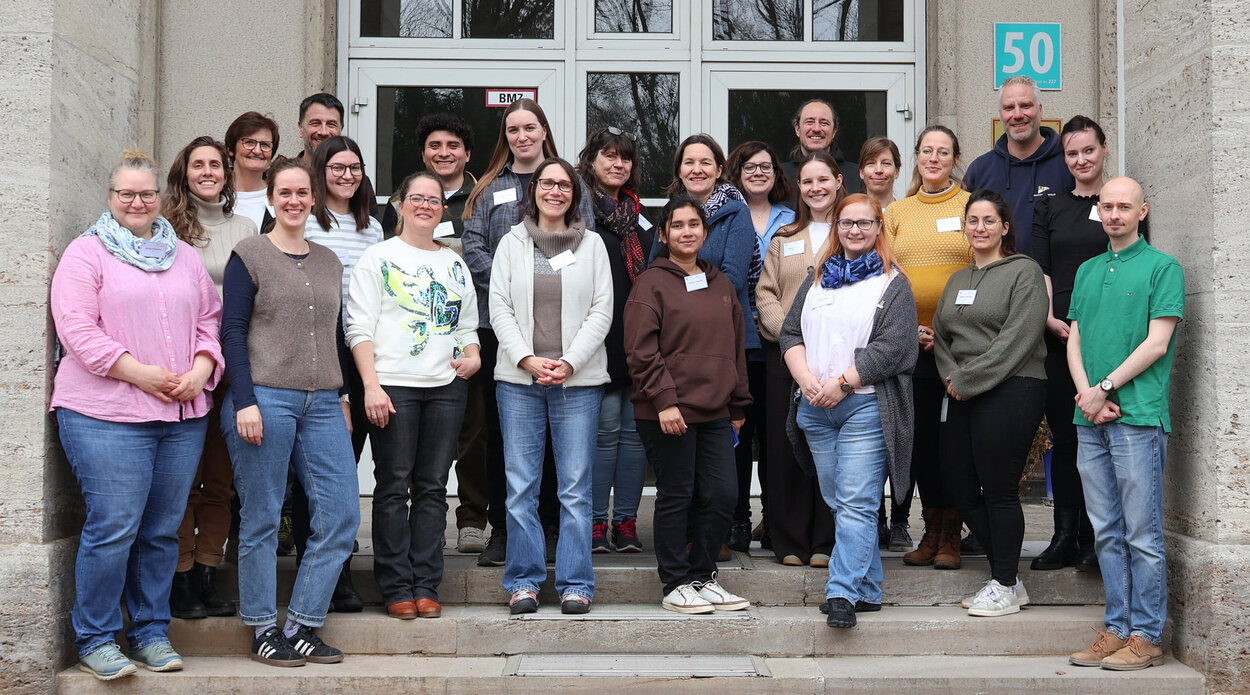 Mehrere Personen stehen vor einem Gebäude auf Treppen.