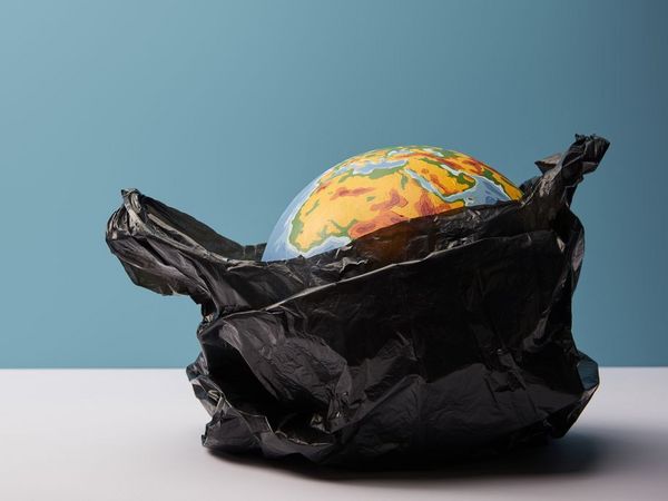 Ein Symbolbild, die Erde liegt in einer schwarzen Plastiktüte