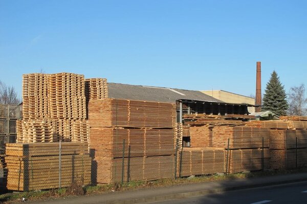 Stapel mit Schnittholz und Paletten liegen auf einem Hof im Freien
