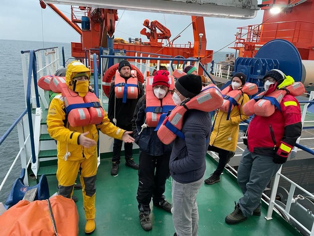 Mehrere Personen mit Rettungswesten auf einem Schiff.