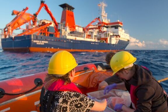 Kristina Koch und Masterstudentin des Alfred-Wegener-Institutes Imke Petersen bei der Beprobung von treibenden Sargassum-Pflanzenteilen. Im Hintergrund das Forschungsschiff.