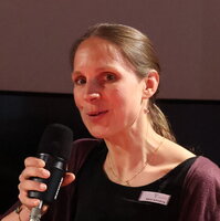 Portait einer Frau mit Mikrofon in der Hand.